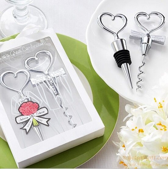 two bottle openers are sitting on a plate next to some flowers and wine glasses