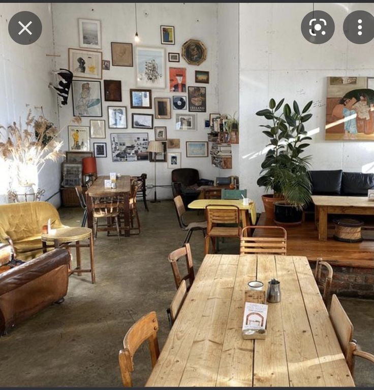 a room filled with lots of furniture and pictures on the wall next to a wooden table