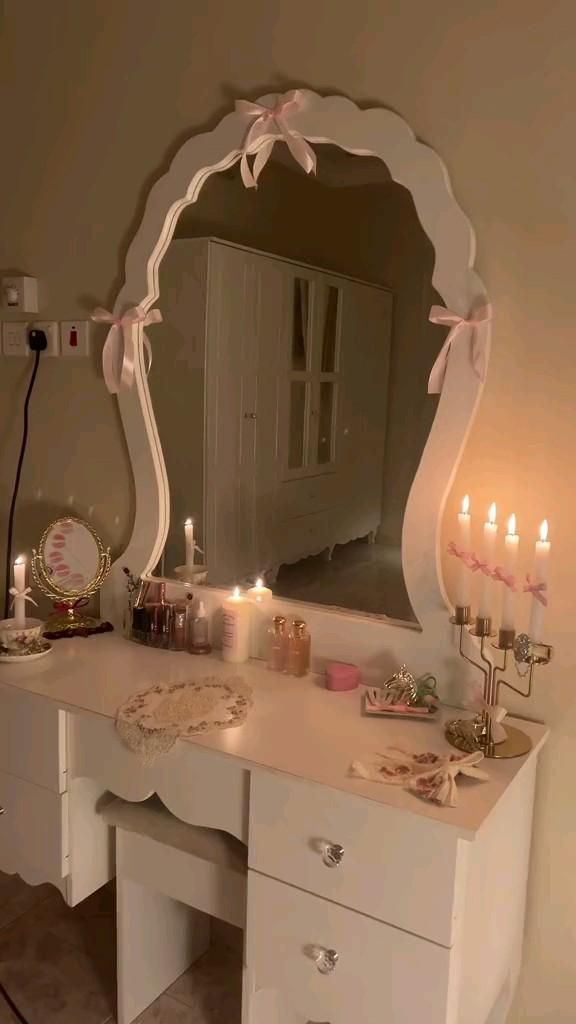 a white vanity with candles on it in front of a mirror that has been decorated