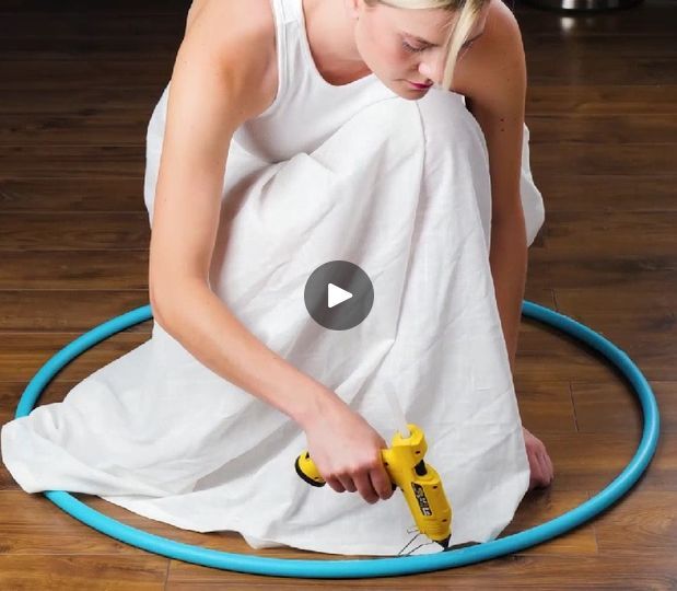 a woman in white dress holding a yellow and blue blow dryer on top of a wooden floor