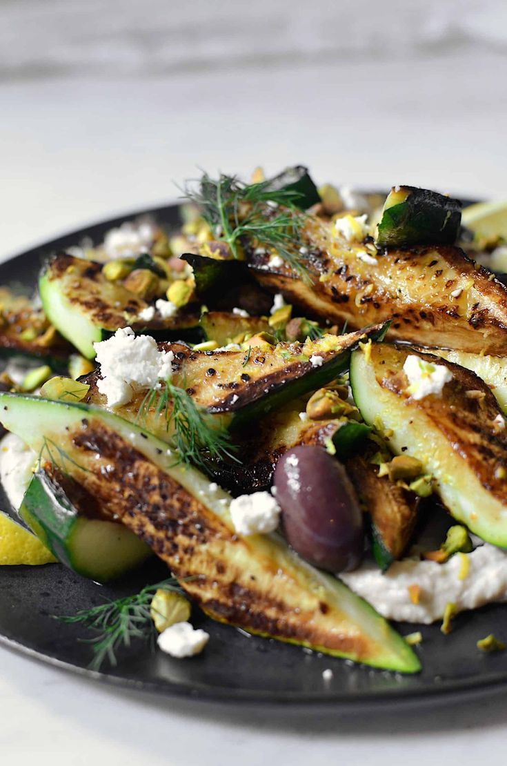 a black plate topped with cucumbers and feta cheese