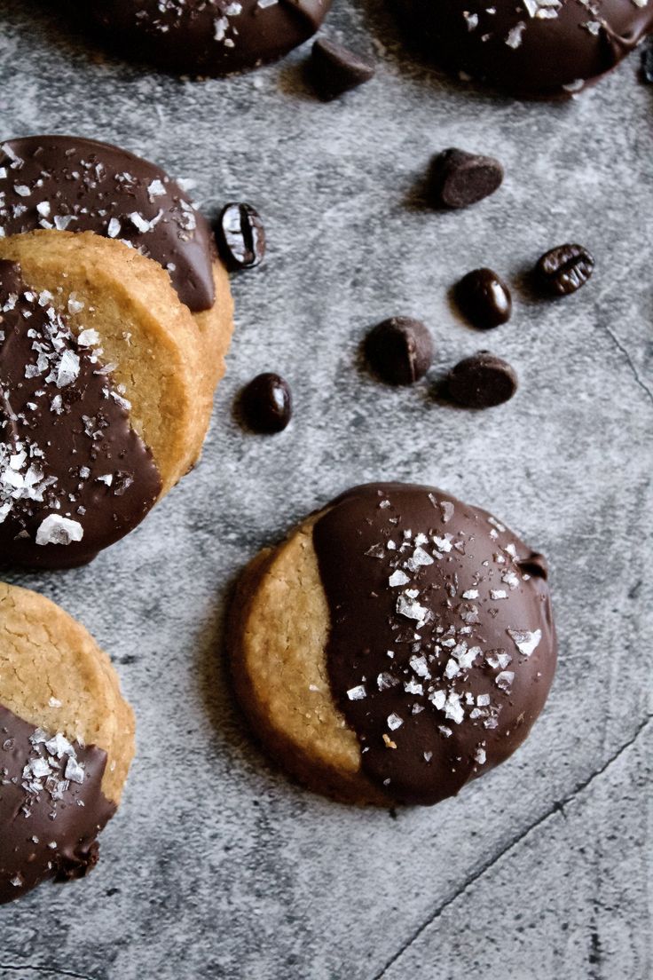 chocolate covered cookies with sea salt sprinkles on a gray surface next to more cookies