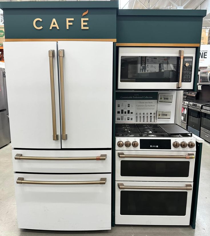 two ovens and a microwave are on display in a store, with the words cafe written above them