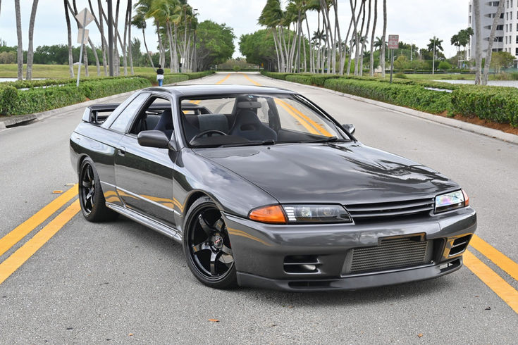 a gray car parked on the side of a road with palm trees in the background