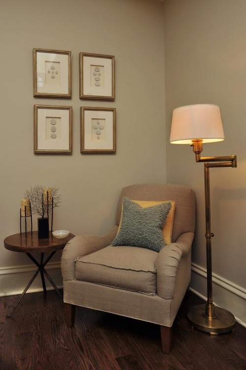 a living room with a chair, lamp and pictures on the wall in it's corner