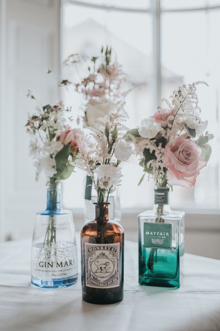 three bottles with flowers in them sitting on a table