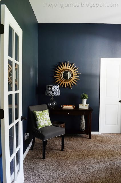 a living room with blue walls and a chair in front of the door that leads to another room