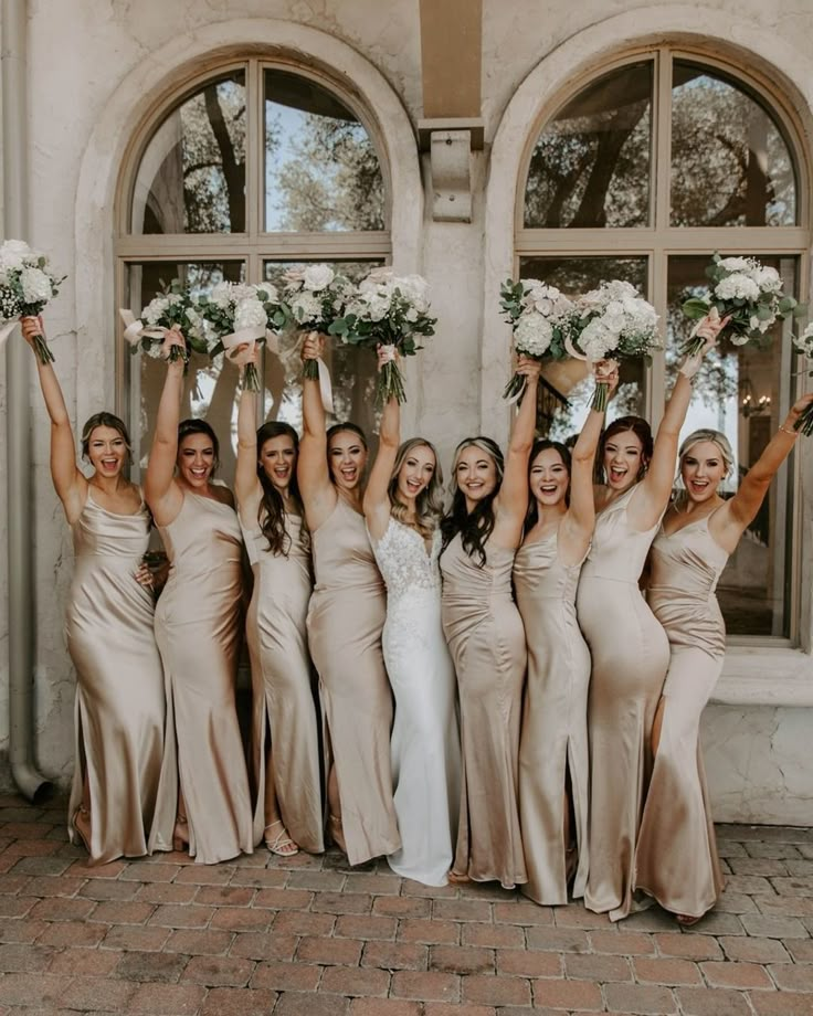 a group of bridesmaids holding their bouquets in the air