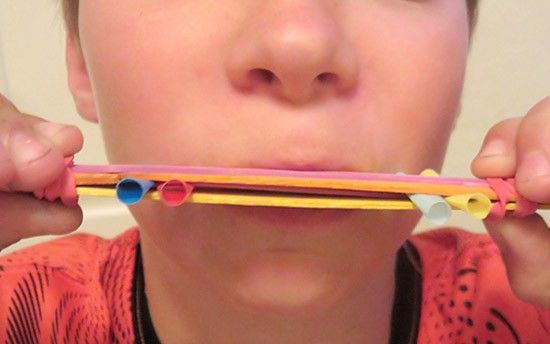 a young boy holding up two toothbrushes to his mouth