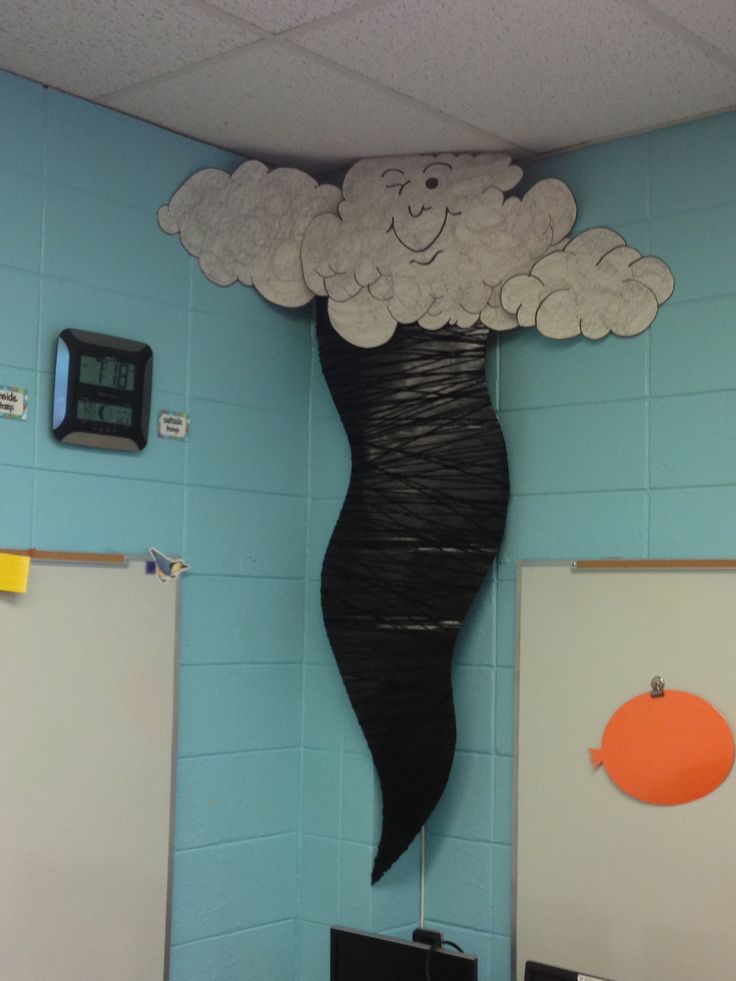 a classroom wall decorated with paper clouds and a smiling face in the shape of a woman's head