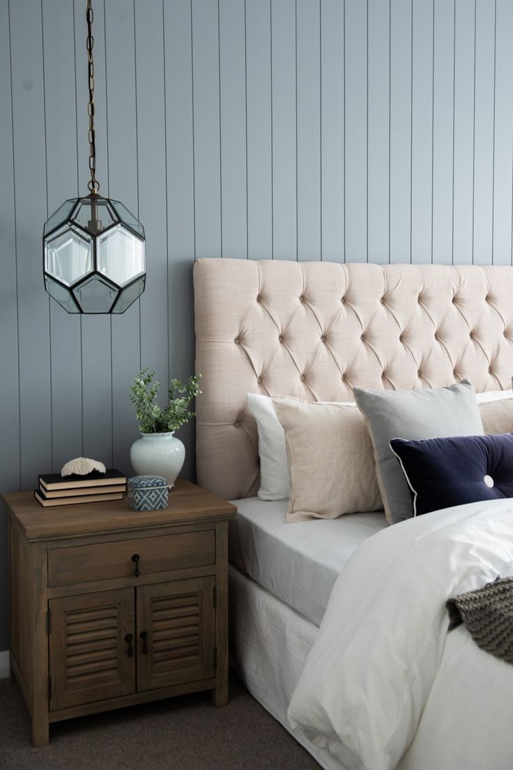 a bed with white linens and blue pillows