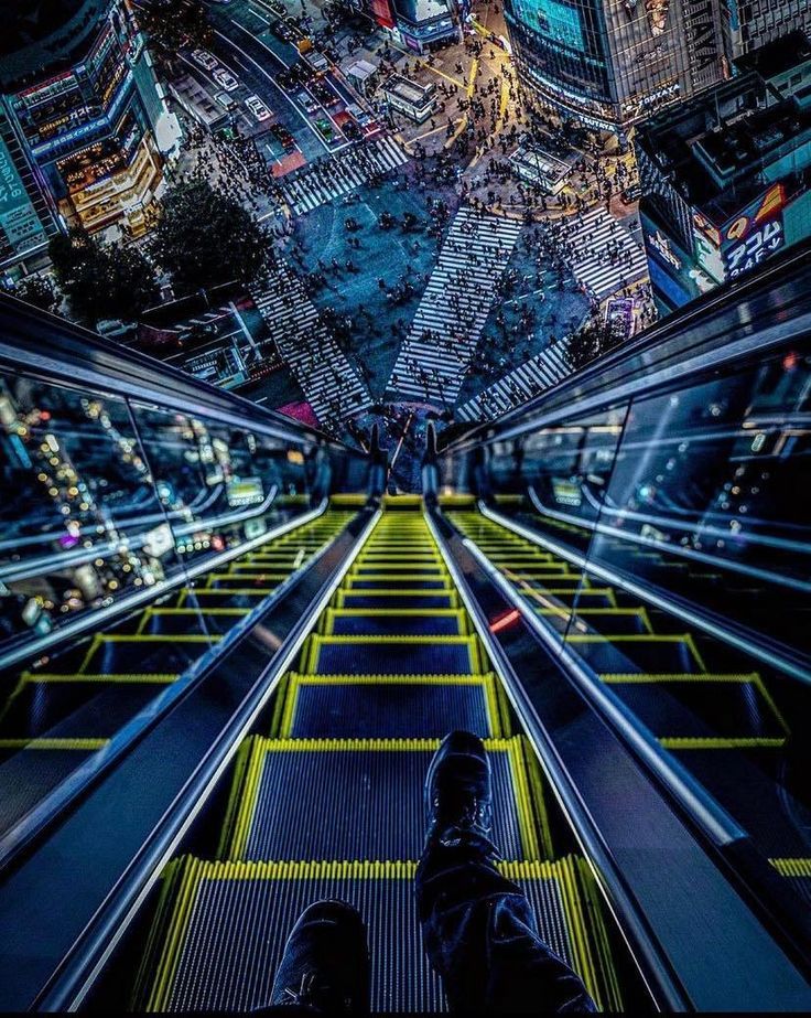 a person standing on an escalator in the middle of a city at night