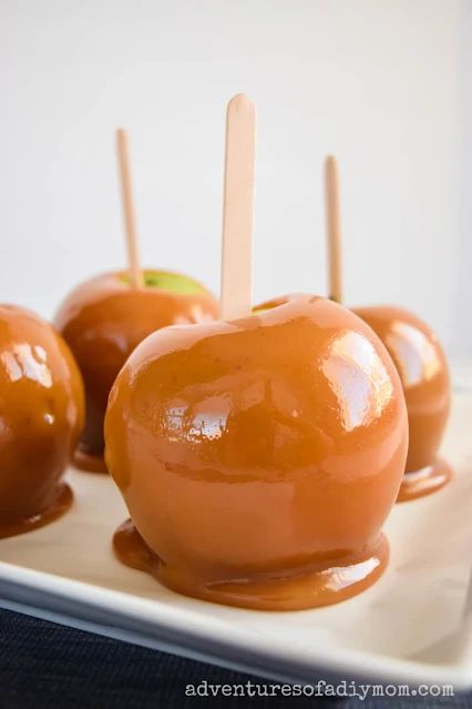 caramel apples with toothpicks on a white plate