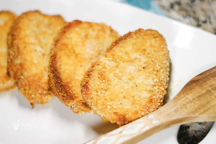 some fried food on a white plate with a wooden spoon