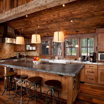 a kitchen with wooden walls and flooring has an island in the middle that is surrounded by stools