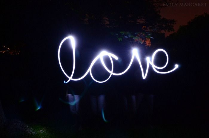 the word love spelled out with light paint in front of a dark night sky and trees