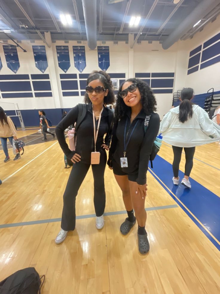 two women standing on a basketball court posing for the camera