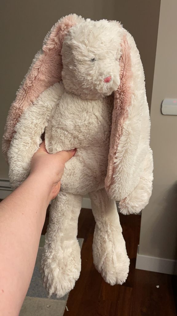 a person holding a white stuffed animal in their hand