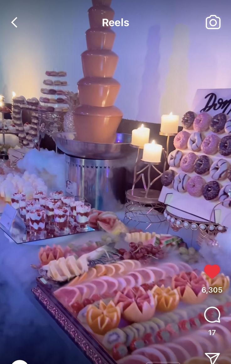 an assortment of pastries on a table in front of a chocolate fountain and candles