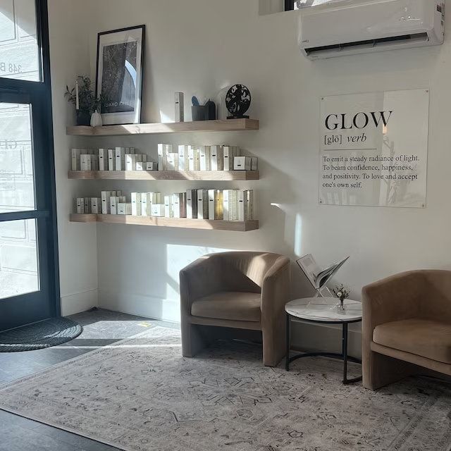 two chairs and a table in a room with shelves on the wall, one is empty