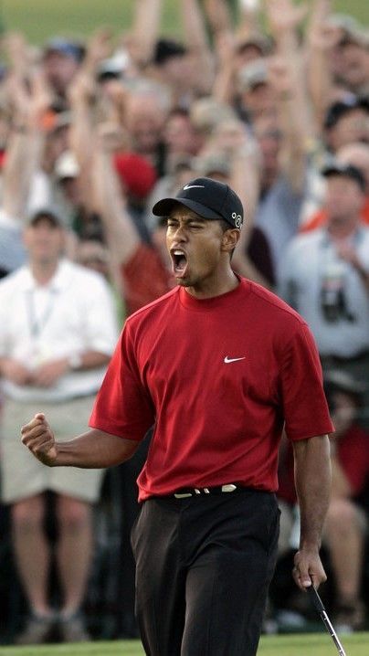 a man in red shirt and black pants holding a golf club with his mouth open