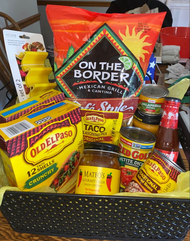 a basket filled with condiments and seasonings on a table next to a bag of chips