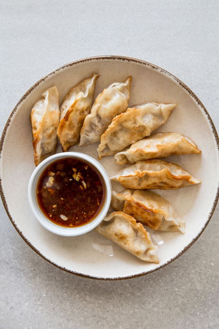 a white plate topped with dumplings and dipping sauce