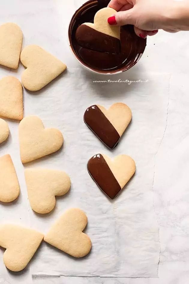 someone is dipping some heart shaped cookies into chocolate