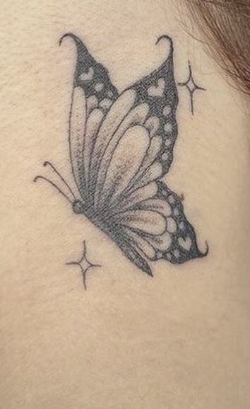 a black and white butterfly tattoo on the back of a woman's neck