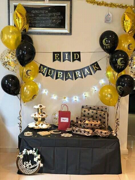 a black table topped with lots of balloons next to a sign that says eid mubaran