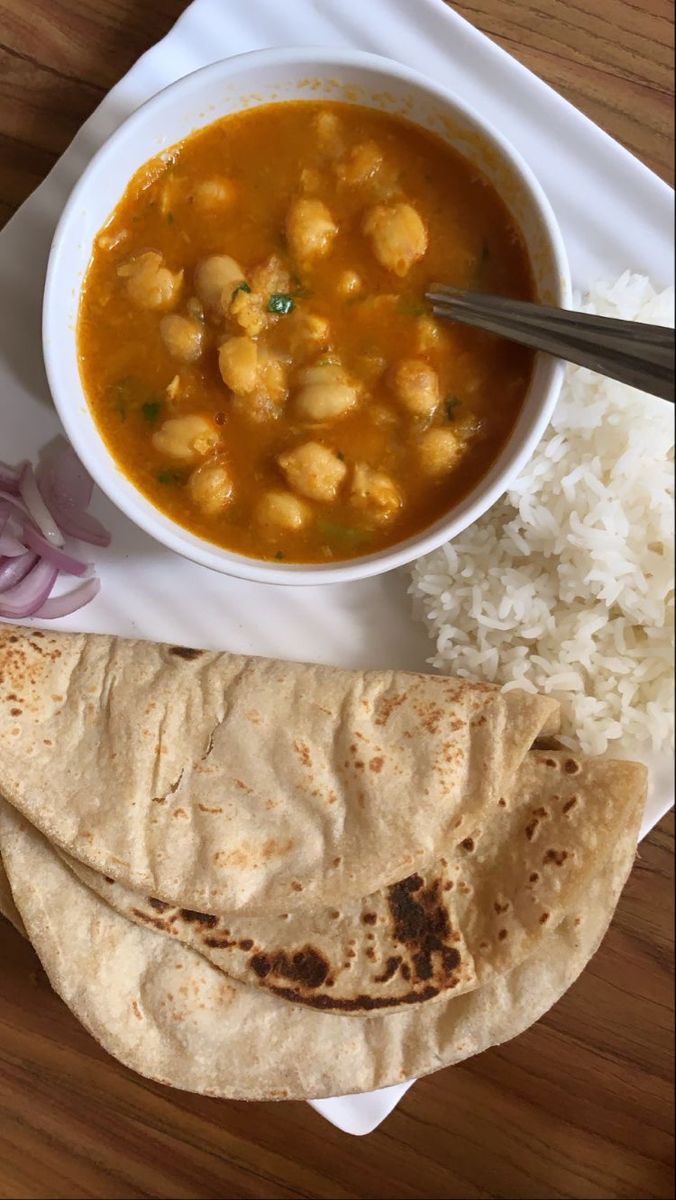 a white plate topped with food next to a bowl of soup and tortilla