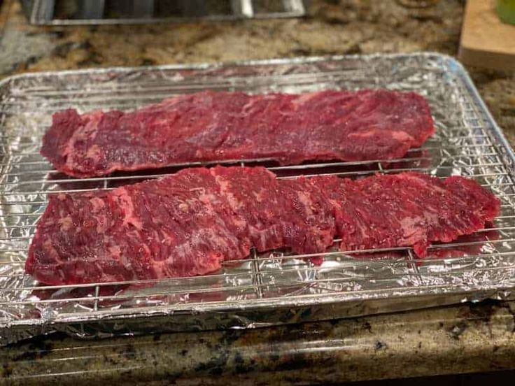 two pieces of raw meat sitting on top of a metal tray