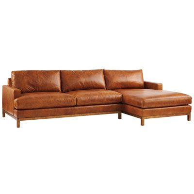 a brown leather sectional sofa sitting on top of a white floor