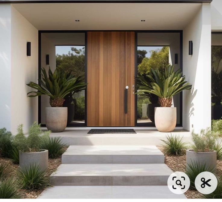 the front entrance to a modern home with potted plants