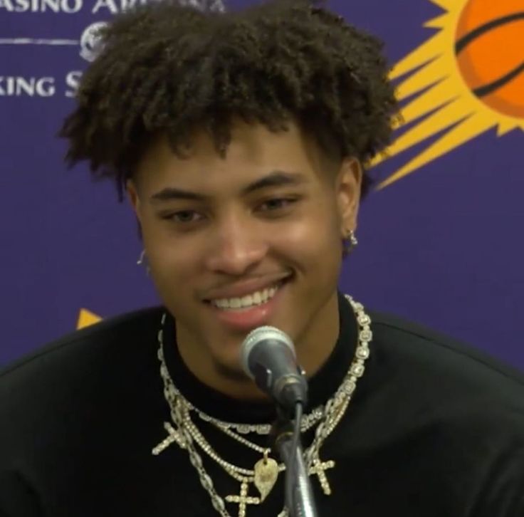 a young man is smiling while speaking into a microphone