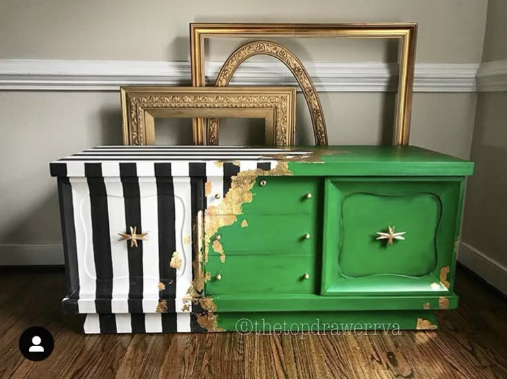 an old dresser painted green and black with gold stars on the top, next to a striped box