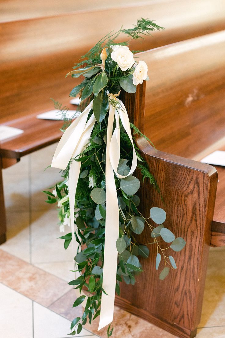 flowers and greenery are tied to the back of a wooden bench