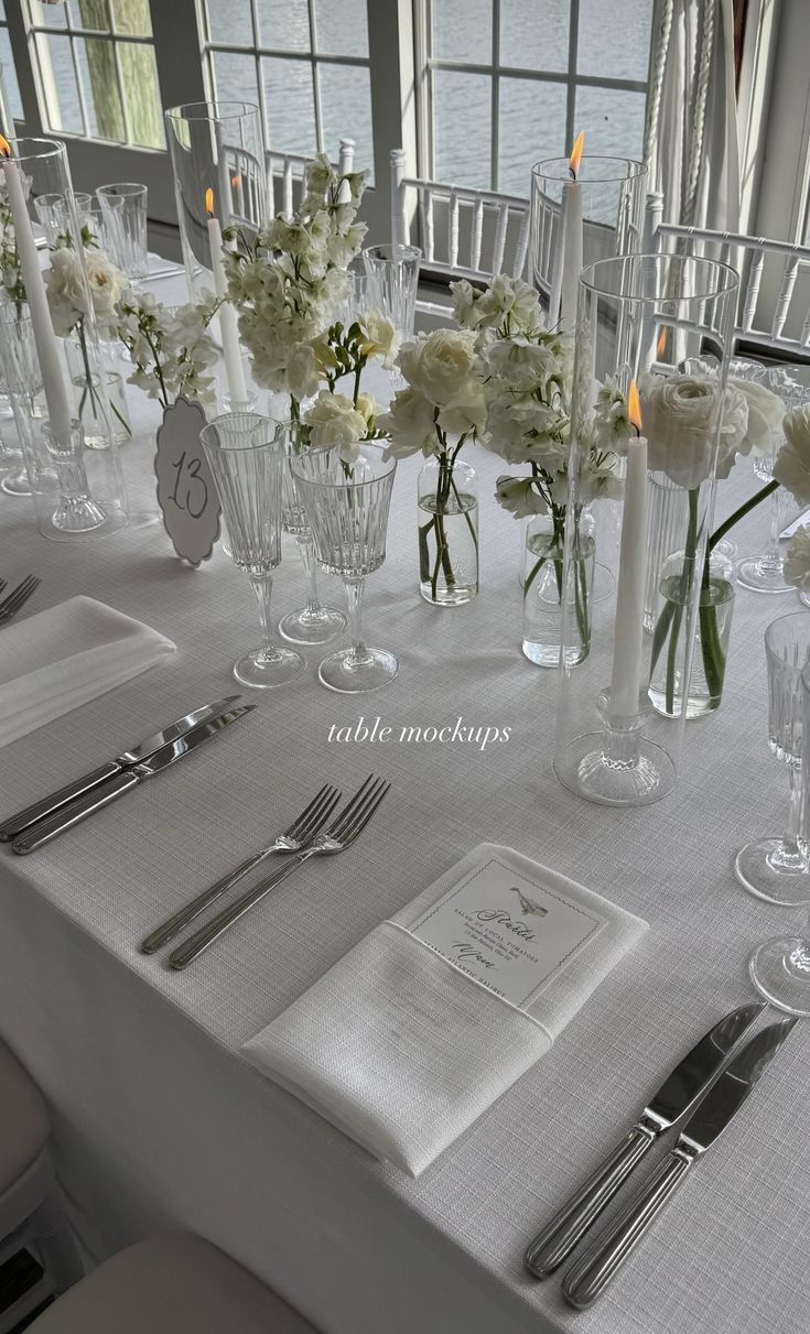 the table is set with white flowers and silverware