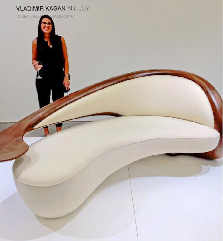 a woman standing next to a white couch with wooden slats on it's sides