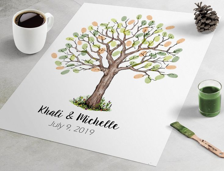 a wedding guest book with a tree on it next to a cup of coffee and pencils