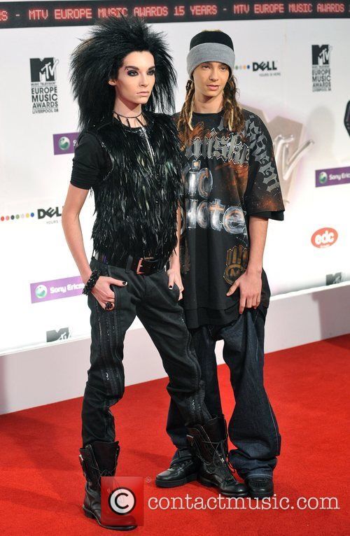 two people standing on a red carpet in front of a wall