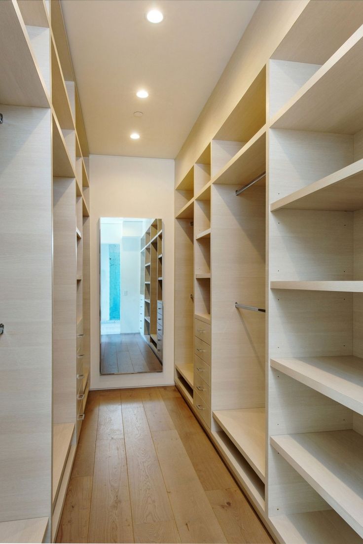 an empty walk - in closet with shelves and lights on the ceiling, along with wooden flooring