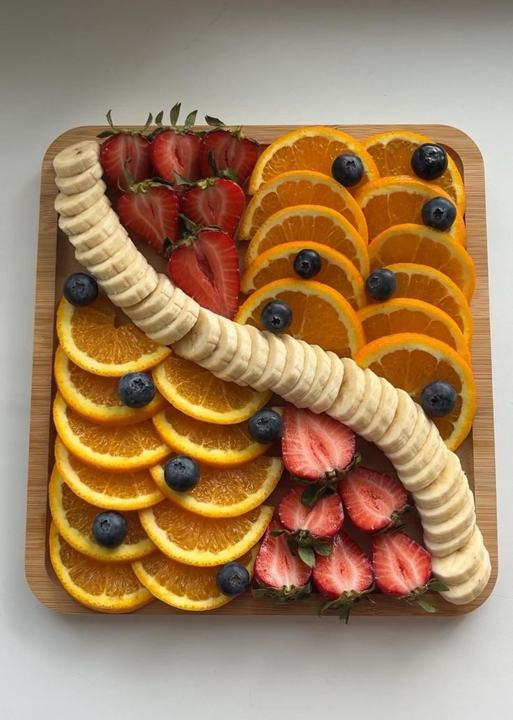 sliced bananas, oranges and strawberries arranged on a platter for a fruit tray