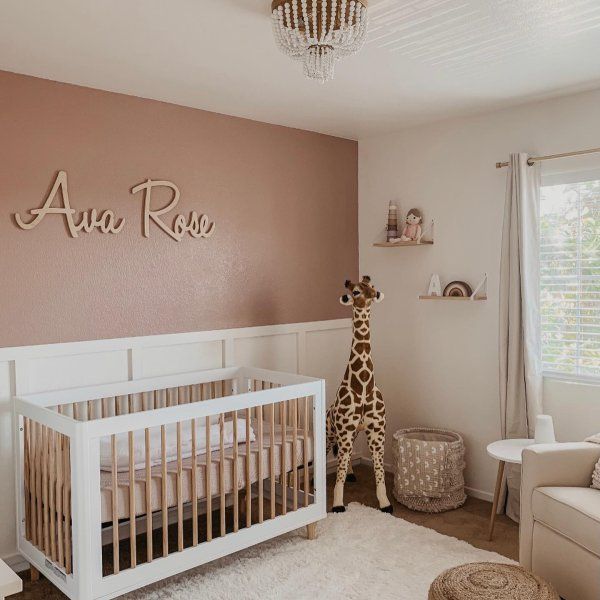 a baby's room with a giraffe in the corner and a name on the wall