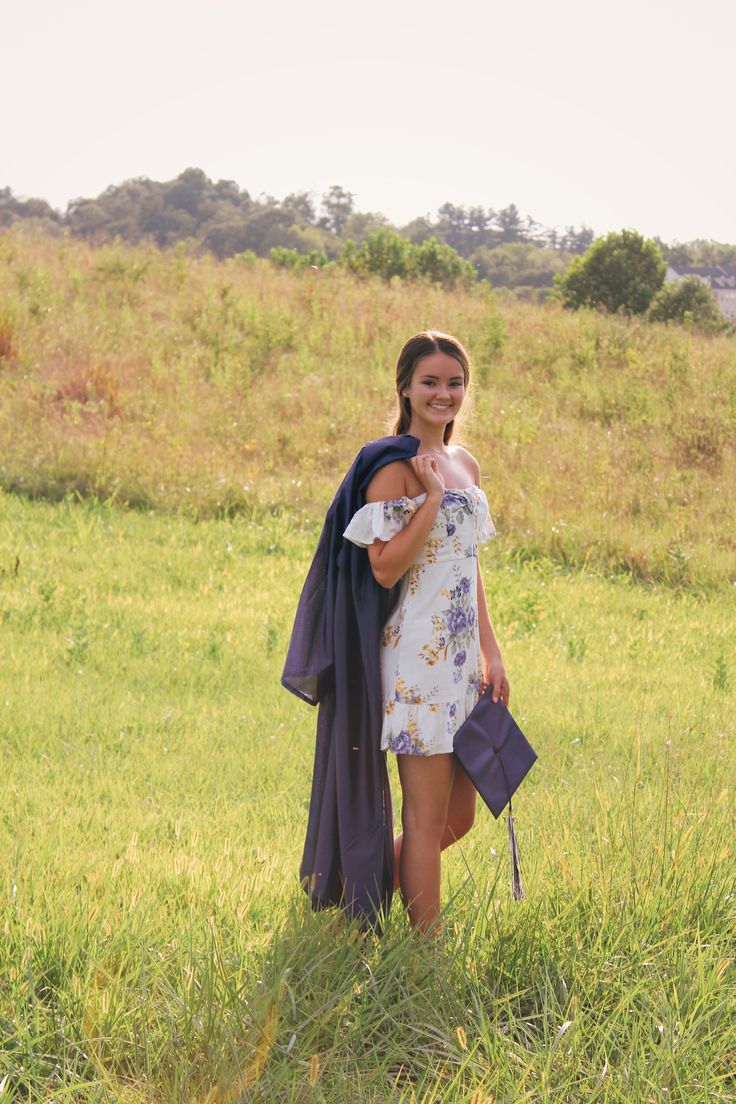 a woman is standing in the grass with her hand on her hip and smiling at the camera