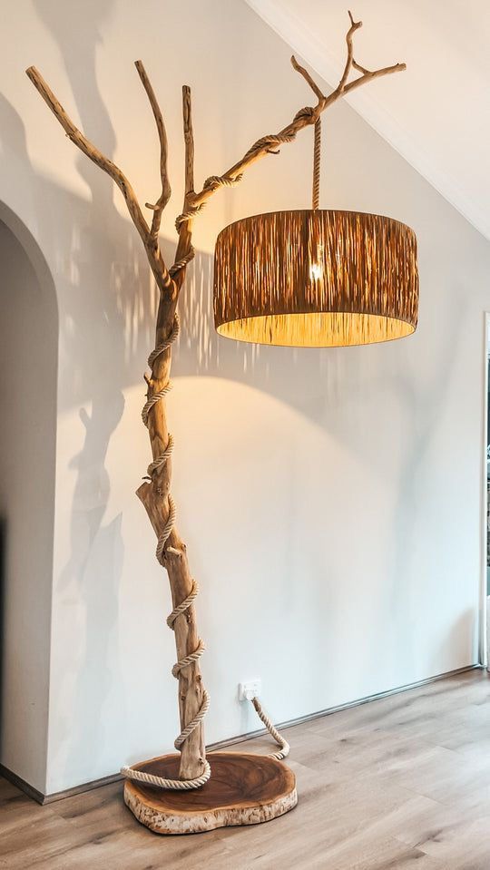 a lamp that is sitting on top of a wooden floor next to a tree trunk