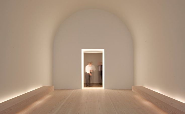 an empty room with white walls and light at the end