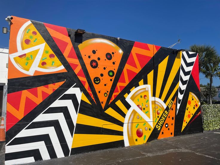 a large colorful mural on the side of a building in front of palm trees and blue sky