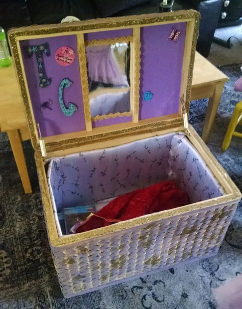 an open white wicker trunk with purple and gold trim