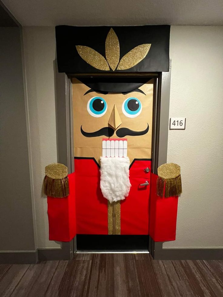 a cardboard nutcracker door decoration with fake hair and mustaches on it's head